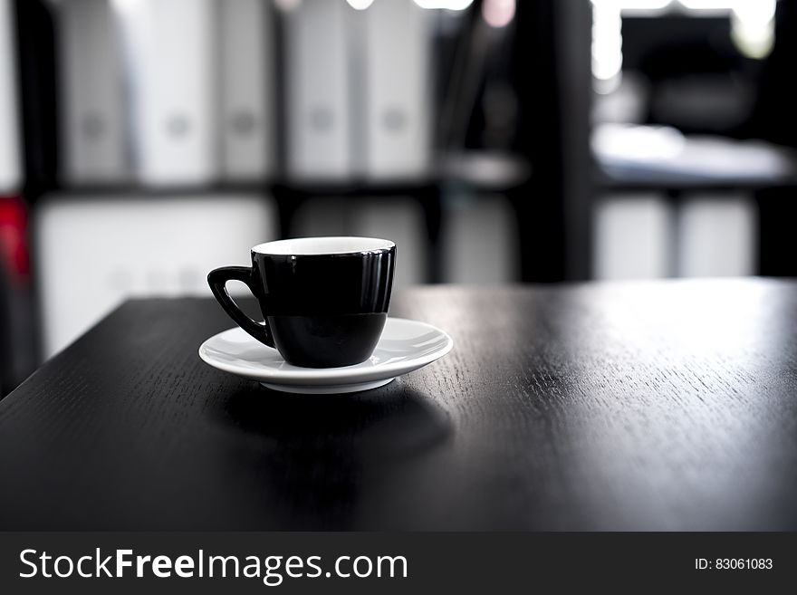 Black and White Ceramic Tea Cup With Saucer on Black Wooden Table