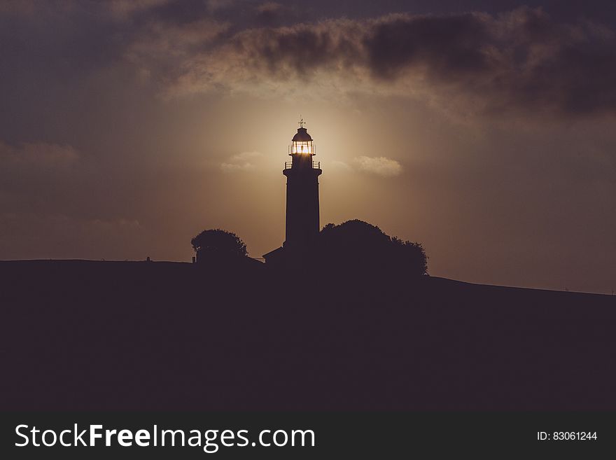 Silhouette of Light House Under Gray Dark Sky