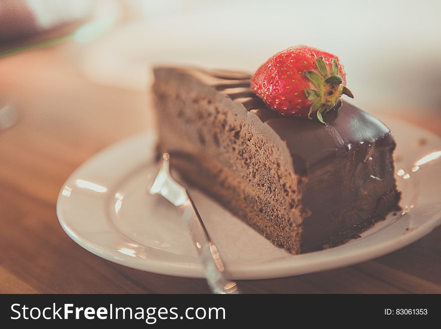 Slice of chocolate cake with fresh ripe strawberry on white china plate with fork. Slice of chocolate cake with fresh ripe strawberry on white china plate with fork.