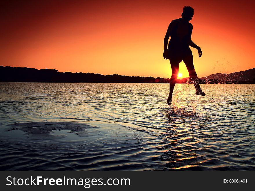 Silhouette of person jumping into water at sunset. Silhouette of person jumping into water at sunset.