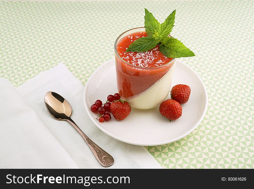 Strawberry parfait in glass with fresh berries and mint sprig.