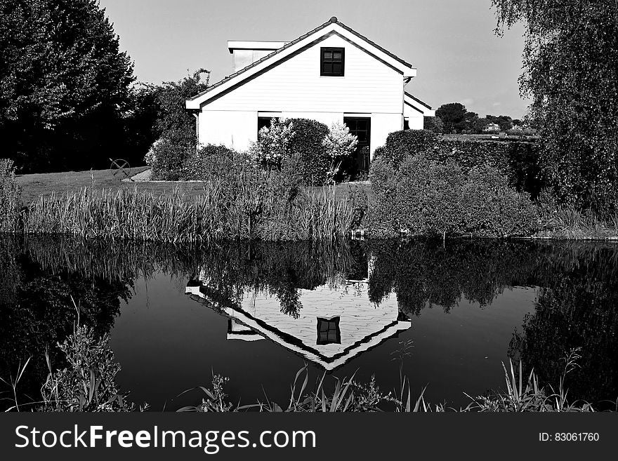 Exterior of white house reflecting in water in black and white.