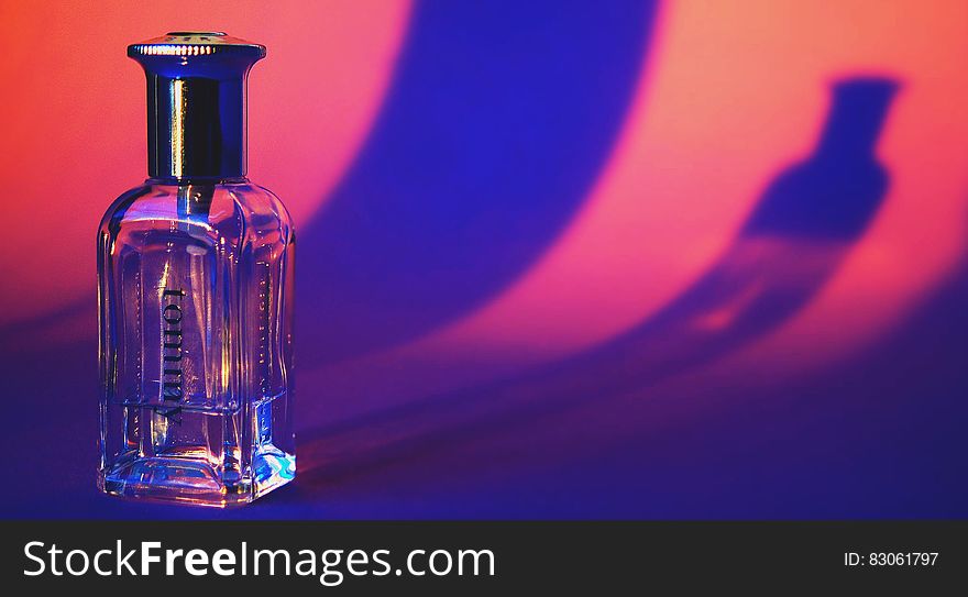 A close up of a transparent half empty perfume bottle.