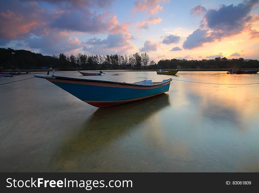 Wooden Boat In Water At Sunset