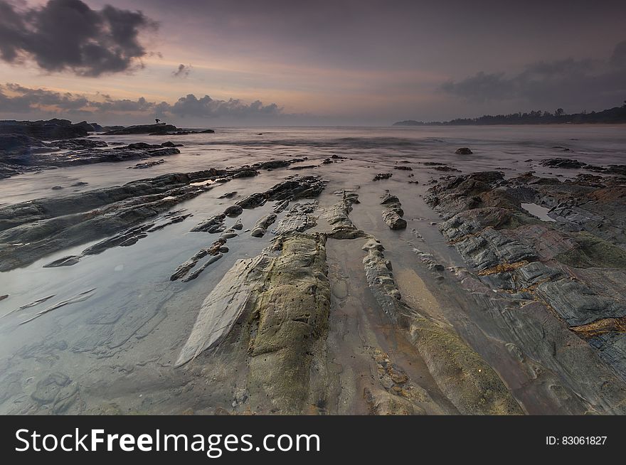 The sunset on the seashore with tide revealing rocks. The sunset on the seashore with tide revealing rocks.