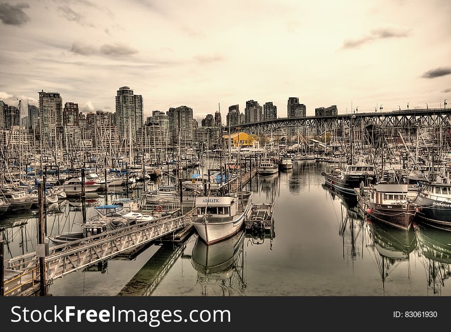 Boats along docks in urban marina with modern skyline on sunny day. Boats along docks in urban marina with modern skyline on sunny day.