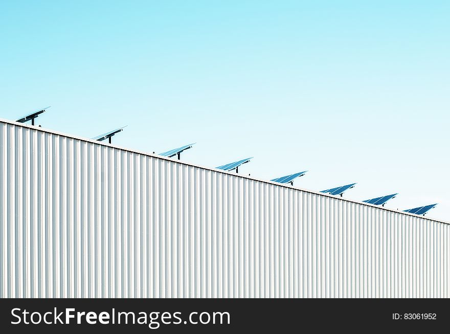 Solar panels on rooftop of corrugated metal building against blue skies on sunny day. Solar panels on rooftop of corrugated metal building against blue skies on sunny day.