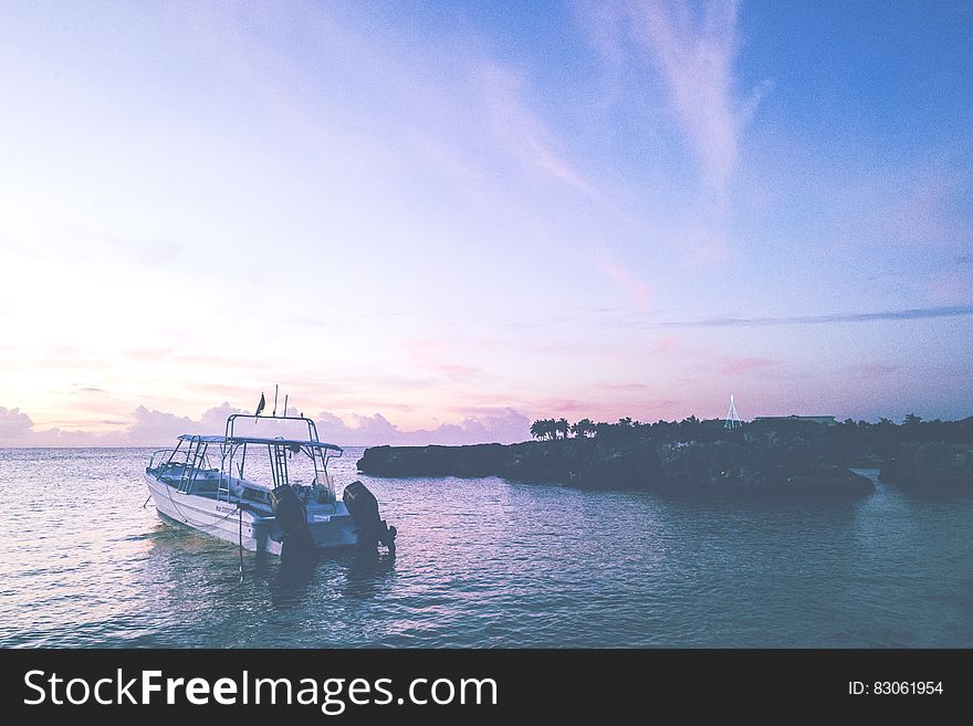 Boat Off Coastline At Sunset