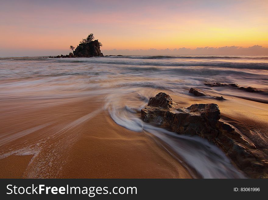Rocks on sandy beach at sunset