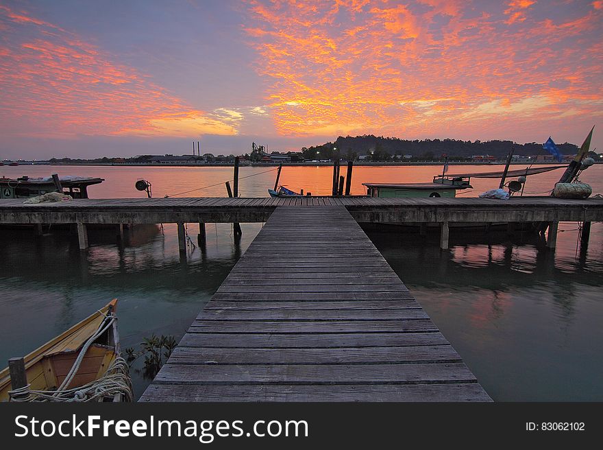 A wood jetty with boats at sunset. A wood jetty with boats at sunset.