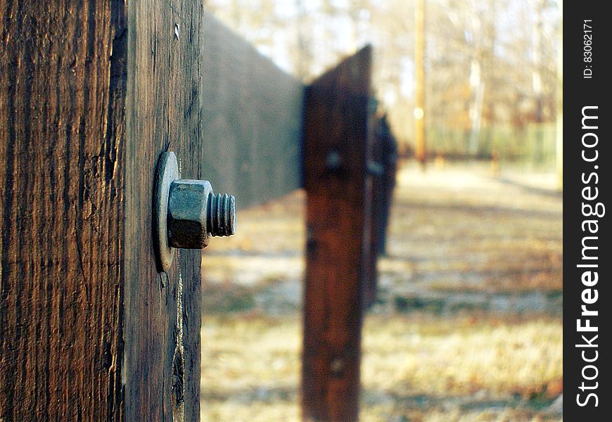Selective Focus Photography of Grey Bolt Pierced in Brown Wooden Fence during Daytime