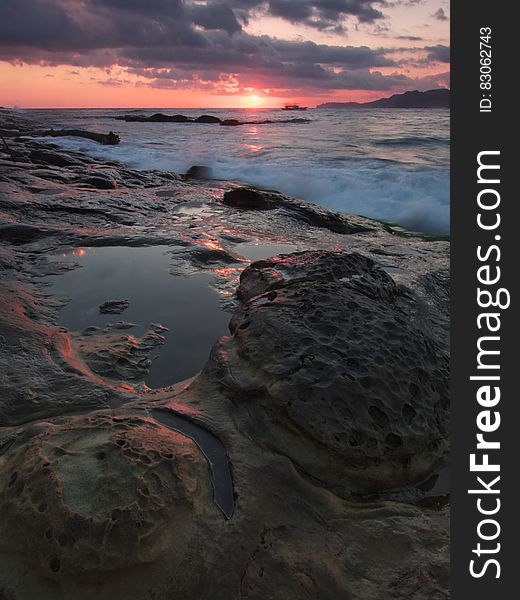 Gray And Black Rock Formation Near The Ocean During Sunset