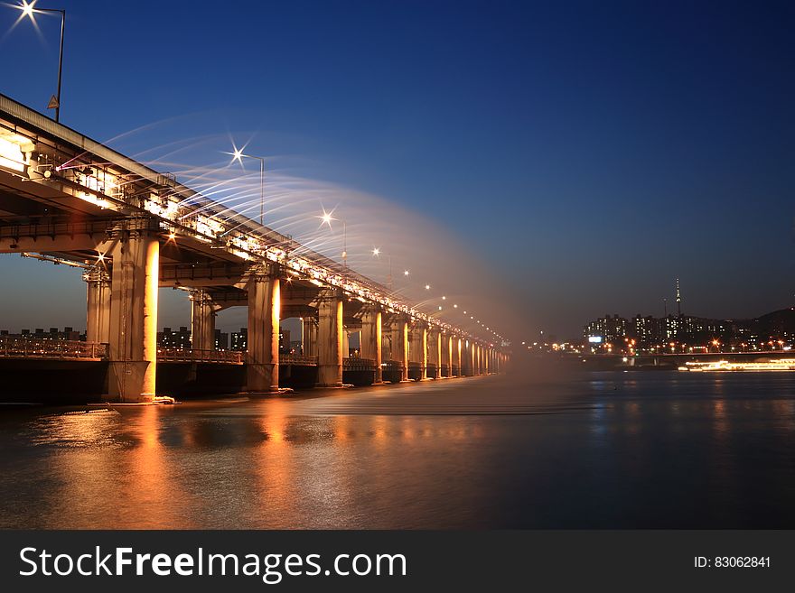 Streetlights illuminated on modern bridge with city skyline at night. Streetlights illuminated on modern bridge with city skyline at night.