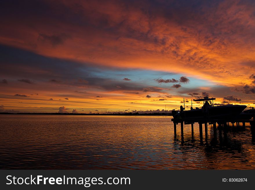 Silhouetted sea dock and colored sky reflecting on sea surface at sunset. Silhouetted sea dock and colored sky reflecting on sea surface at sunset.