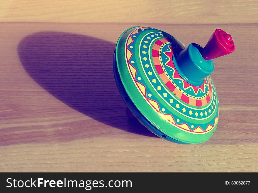 A close up of a colorful whipping top on a wooden background.