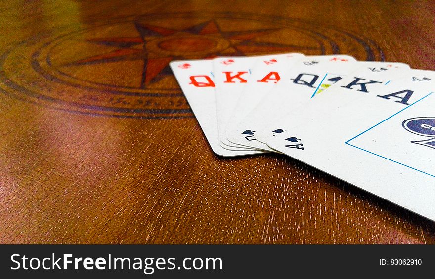 Ace, King, Queen of spades and Ace, King Queen of diamonds laid out in a fan on a wooden gaming table. Ace, King, Queen of spades and Ace, King Queen of diamonds laid out in a fan on a wooden gaming table.