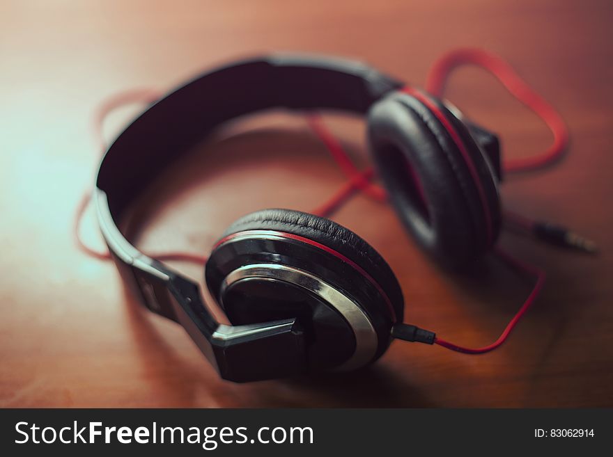 Closeup with selective focus of a pair of good quality audio headphones with headband and connecting wires visible.