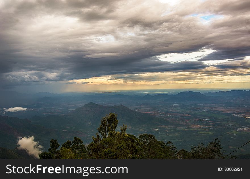 A scenic view from a mountain over valleys with cloudy skies above.
