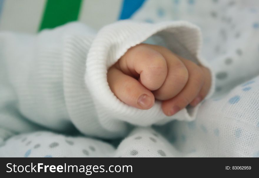 Close up on the hand of baby in white knit sleeve. Close up on the hand of baby in white knit sleeve.