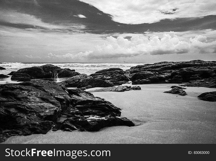 Grayscale Photography of Rocks on Seashore during Daytime