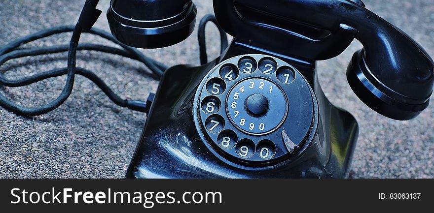 Black Rotary Telephone at Top of Gray Surface