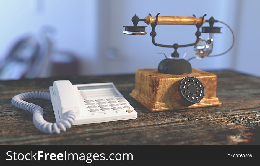 White Electric Home Phone Close To Rotary Phone On Table