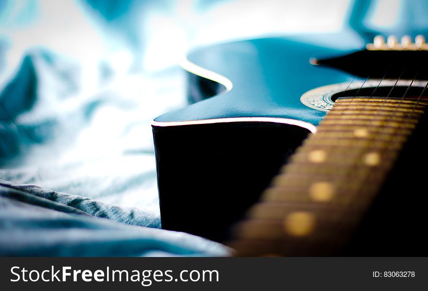 Black Acoustic Guitar in Grey Textile Close Up Photo
