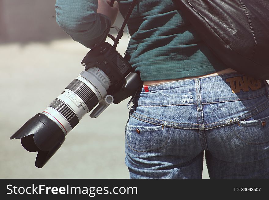 Photographer carrying camera with zoom lens on shoulder outdoors. Photographer carrying camera with zoom lens on shoulder outdoors.
