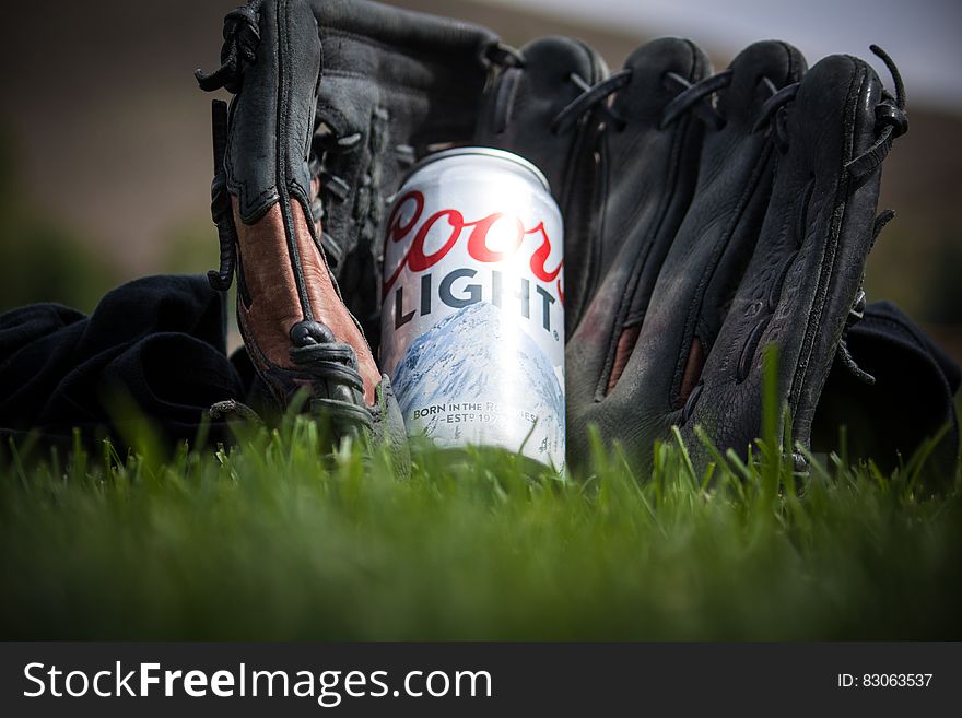 Close Up Photography of Coors Light Beer Near Black Baseball Mitts