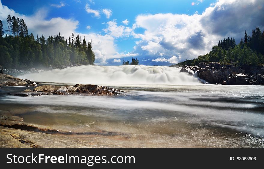 River Near Trees Under Blue Sky and White Clouds