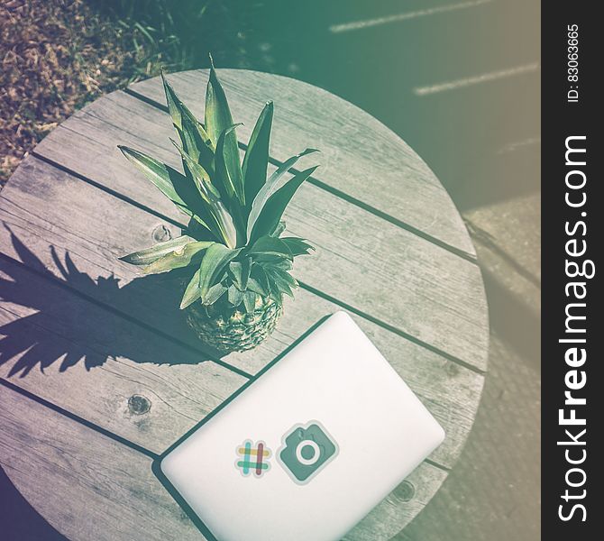 Pineapple Fruit Near White Laptop Computer on Brown Wooden Table