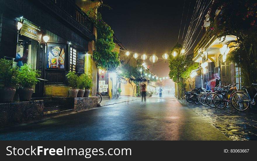 Person Standing On Gray Path Way Near Bicycles During Night Time