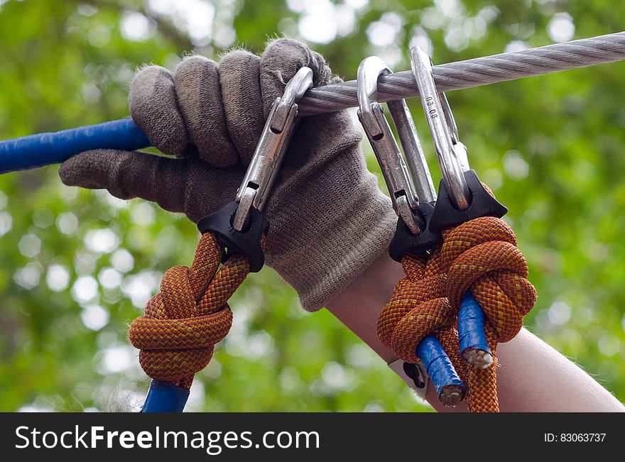 Person in Gray and Beige Gloves Holding on Gray Cable Wire