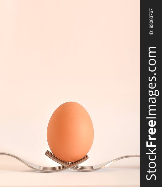 Side view of egg balancing on two forks with studio background and copy space.