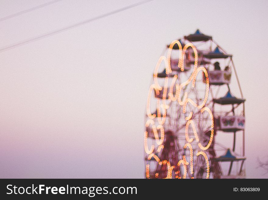 Blur of lights and motion on Ferris Wheel at sunset.