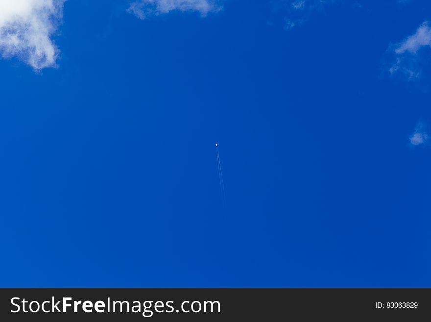 Distant aircraft flying in blue sky with cloudscape.