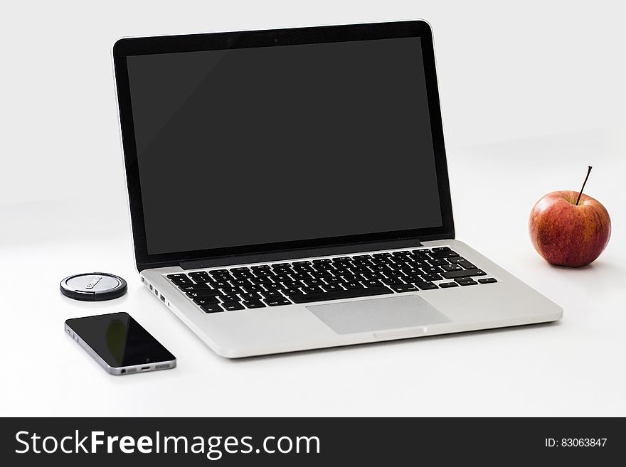 Open Macbook next to ripe apple and smartphone, white background. Open Macbook next to ripe apple and smartphone, white background.