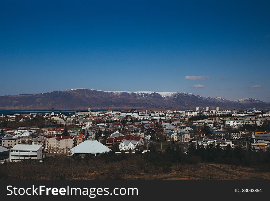 Scenic view of Icelandic town with snow capped mountains in background.