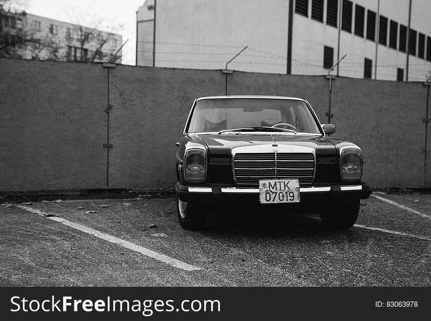 Monochrome view of German Mercedes Benz car parked next to wall with security wire.