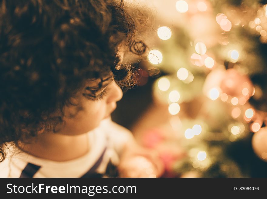 Portrait of child with brown curly hair using selective focus on one eye looking at a blur of Christmas tree lights. Portrait of child with brown curly hair using selective focus on one eye looking at a blur of Christmas tree lights.