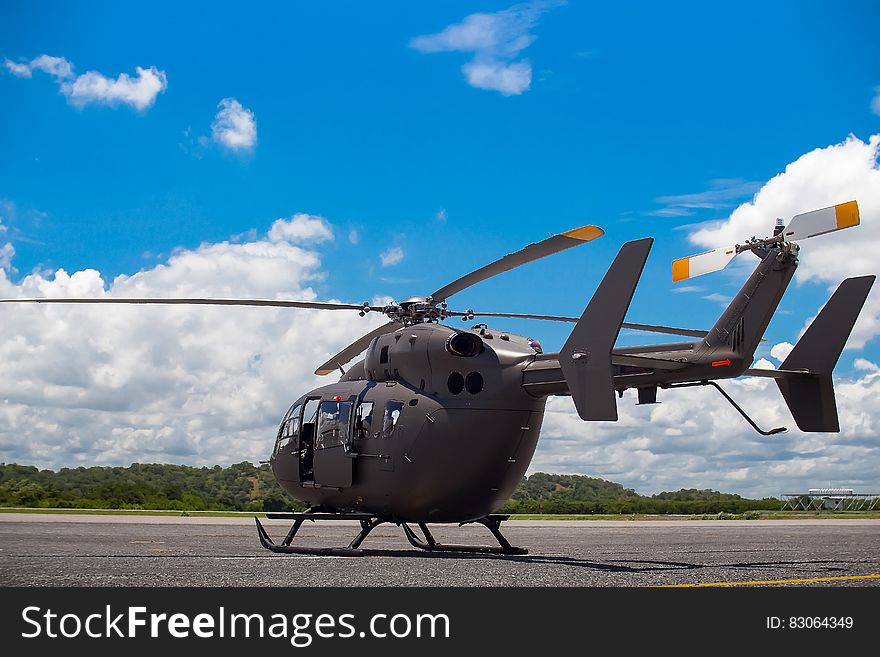 Military helicopter sitting on pad on sunny day with blue skies. Military helicopter sitting on pad on sunny day with blue skies.