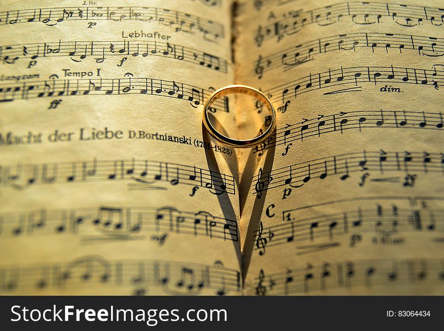 Close up of gold band on open sheets of music score. Close up of gold band on open sheets of music score.