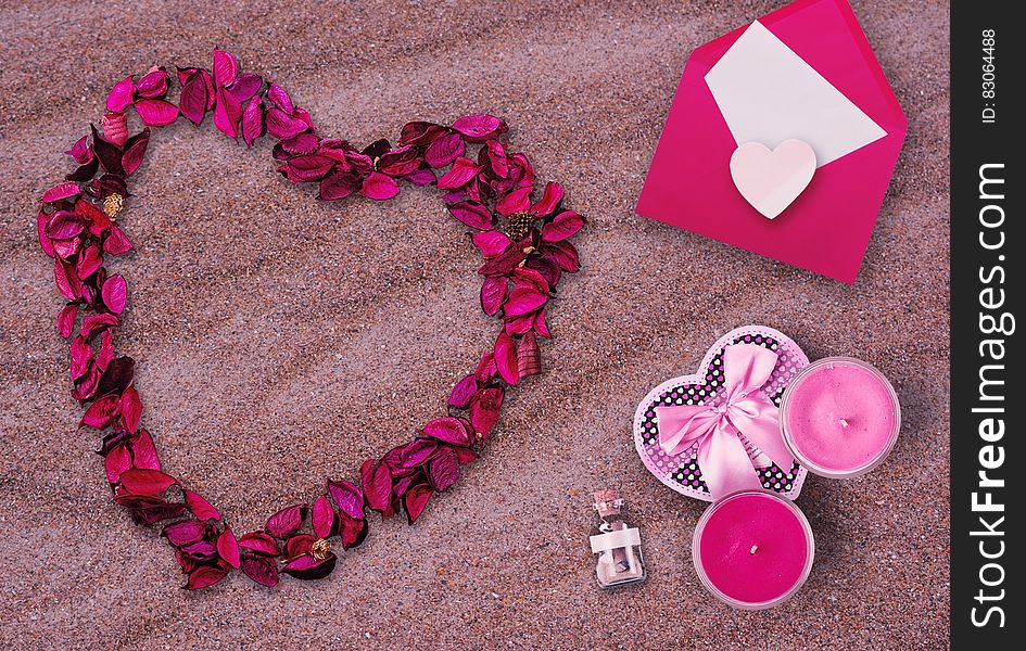 Valentine's Day still life of flower petals in heart shape with card and candles on sand. Valentine's Day still life of flower petals in heart shape with card and candles on sand.