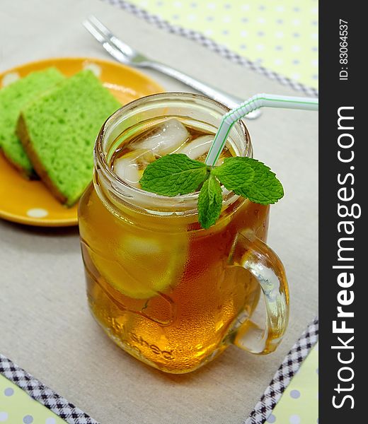 Iced tea with mint in mason jar on table with plate of green cakes.