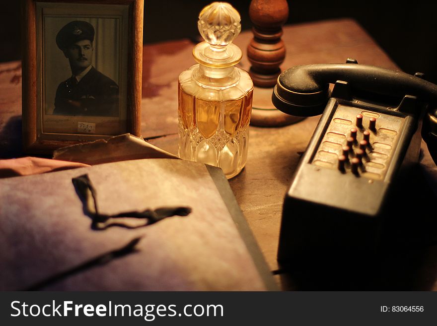 Black and Gray Vintage Telephone Near Glass Perfume Bottle