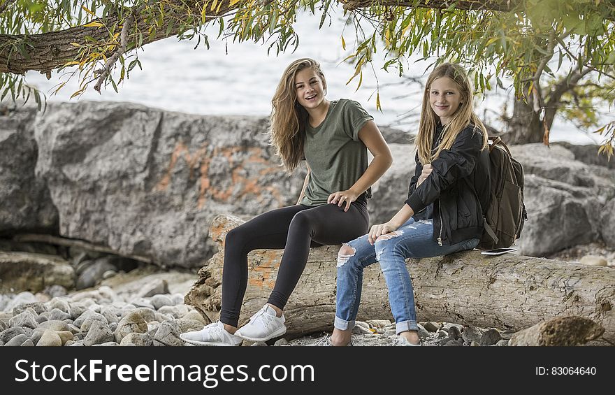 2 Women Sitting on Rock during Daytime