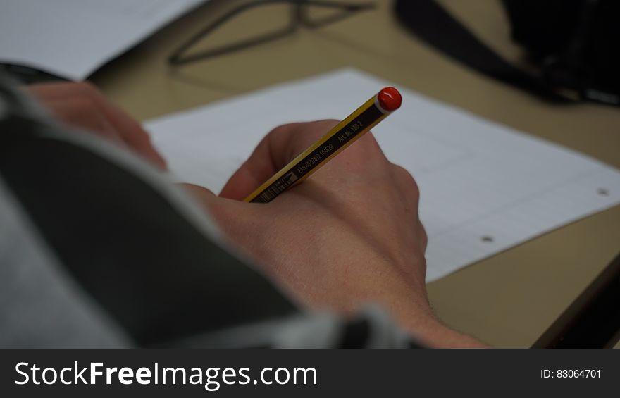 Hand of child writing with wooden pencil on desktop. Hand of child writing with wooden pencil on desktop.