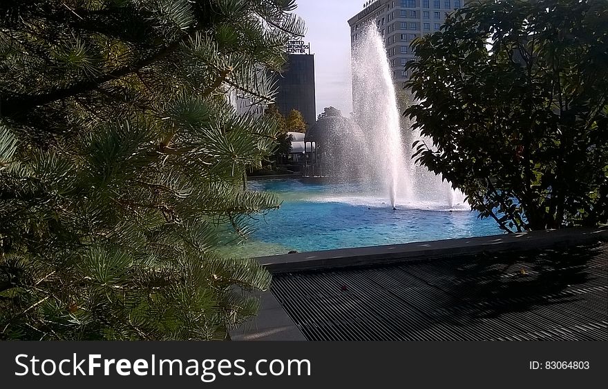 Fountain surrounded by modern architecture in city on sunny day. Fountain surrounded by modern architecture in city on sunny day.