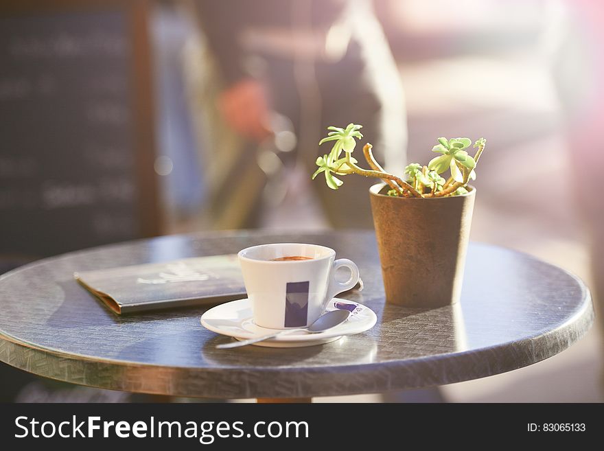 Cup Of Coffee On Table Beside Plant