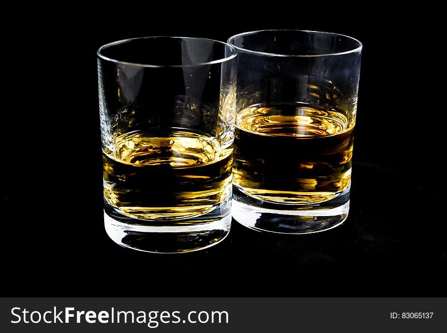 Glasses of whiskey on black background.